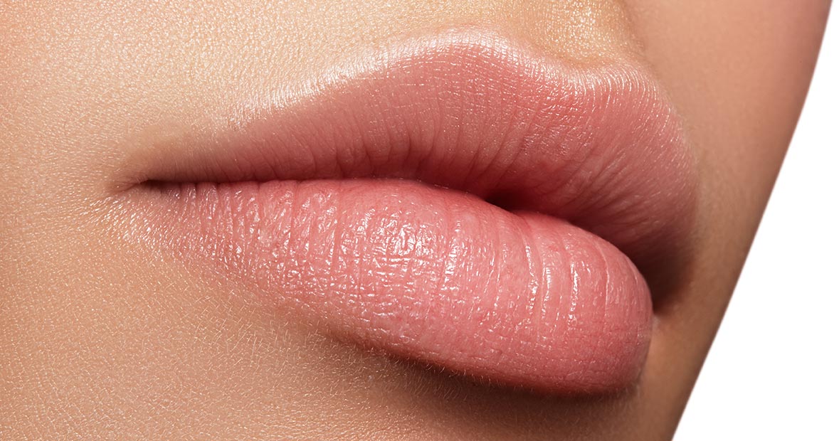 Lips with dermal fillers appear to be pink and full.